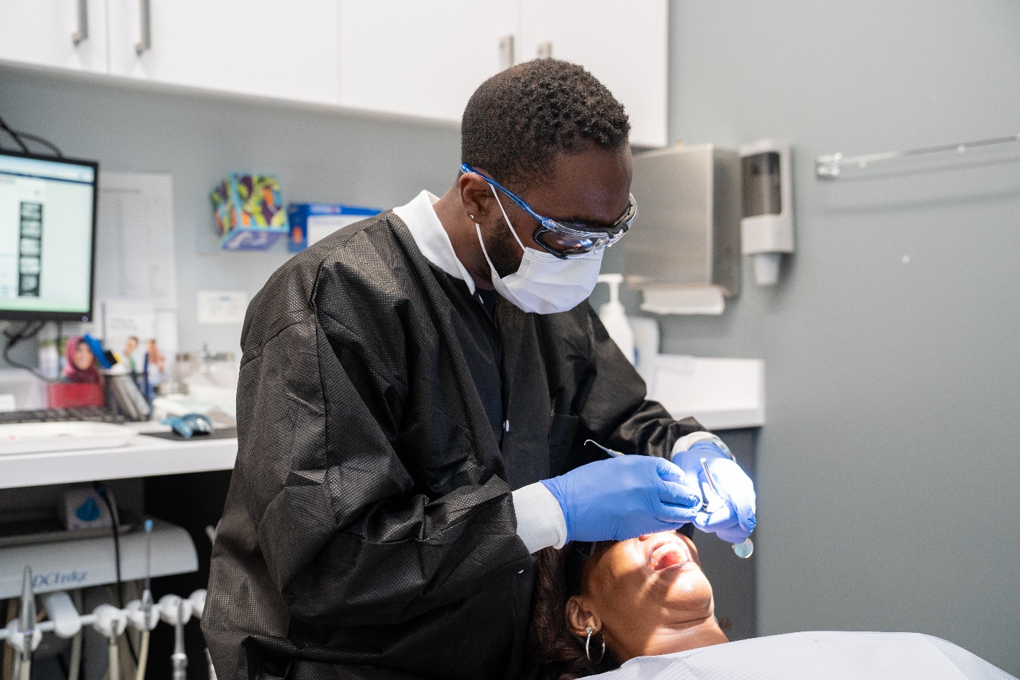 A dental hygienist inspects a woman's mouth during an exam