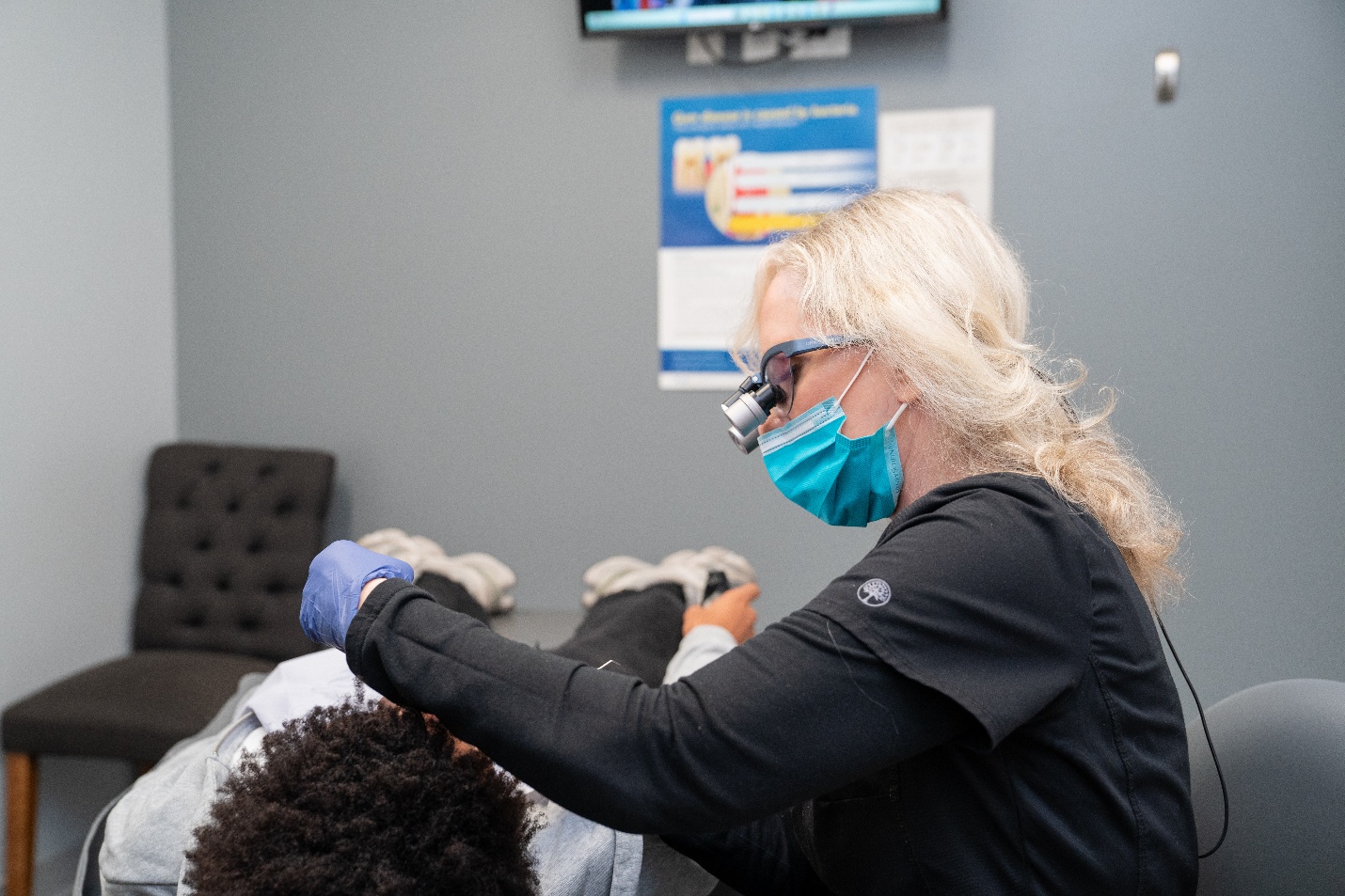 A dental hygienist performs a cleaning on a patient